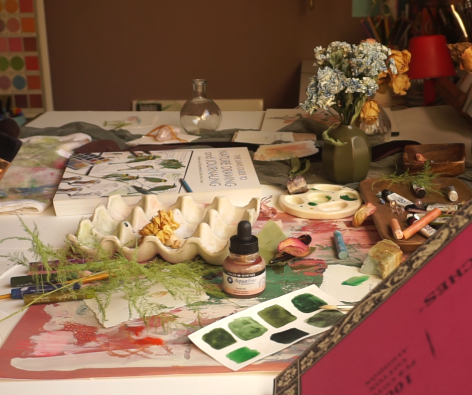 Artist Desk with paint and art book paint swatches and flowers on the table